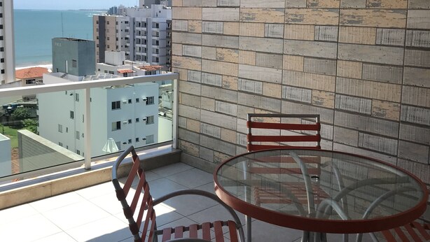 A balcony with a glass table and chairs, a tiled floor, and a view of the sea and buildings. - Spectacular Triplex Penthouse on Morro Beach (ES)
