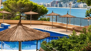 Un espace piscine offrant une vue sur la mer et sur le paysage urbain en arrière-plan.