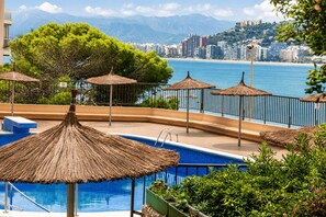 A pool area with a view of the sea and a cityscape in the background.