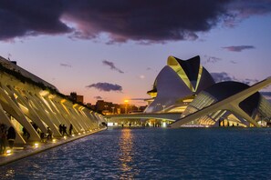 Ein Gebäude am Wasser mit markanter, moderner Architektur, das eine Reihe weißer, geschwungener Strukturen direkt am Ufer aufweist.