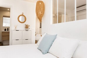 A modern bedroom with a bed, a dresser, a mirror, and a hanging decorative element.