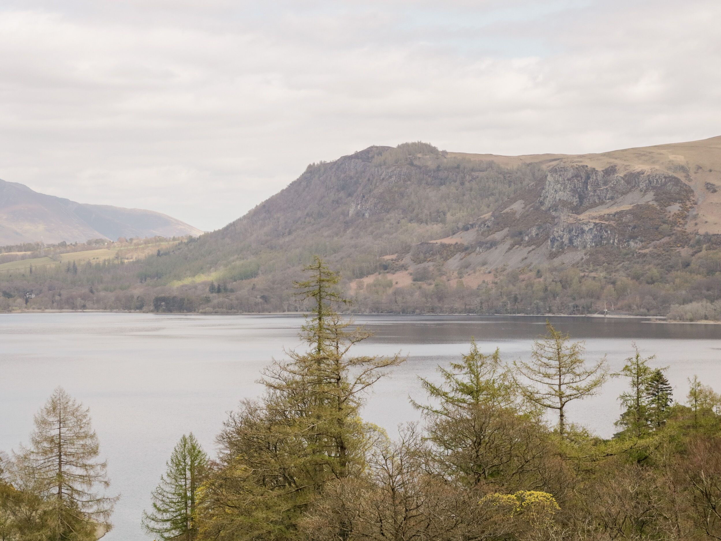 A mountainous landscape with a lake and trees in the foreground.