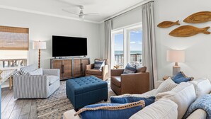 Un salon équipé d’un téléviseur, de canapés, d’une table basse et offrant une vue sur la mer.