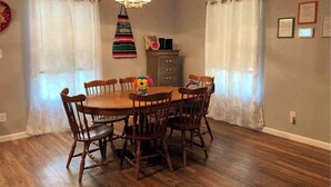 Comedor con mesa y sillas de madera, candelabro y cortinas.