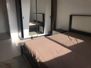 A bedroom with a bed, a wardrobe, a nightstand, and a mirror.