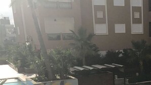 A multi-story residential building with balconies, a central staircase, and a small courtyard with palm trees. - Superb studio for vaccinations (Sousse)