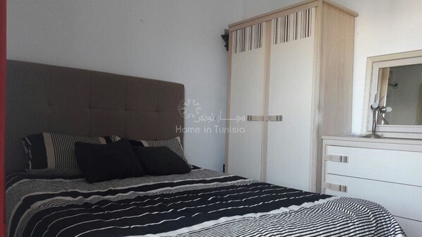 A bedroom with a bed, a wardrobe, and a mirror.
