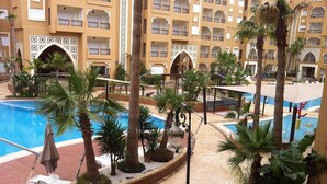 A hotel courtyard with a swimming pool, palm trees, and a decorative archway. - Superb studio for vaccinations (Sousse)