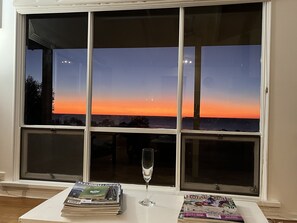 Une pièce dotée d’une grande fenêtre donnant sur un coucher de soleil.