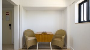 Une petite pièce avec une table en bois et deux chaises en osier, une porte avec une pancarte et une fenêtre.