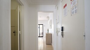 Un couloir avec une armoire en bois, une porte et un luminaire fixé au mur.