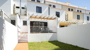 Un bâtiment blanc doté de balcons, d’un patio couvert et d’un petit espace verdoyant.