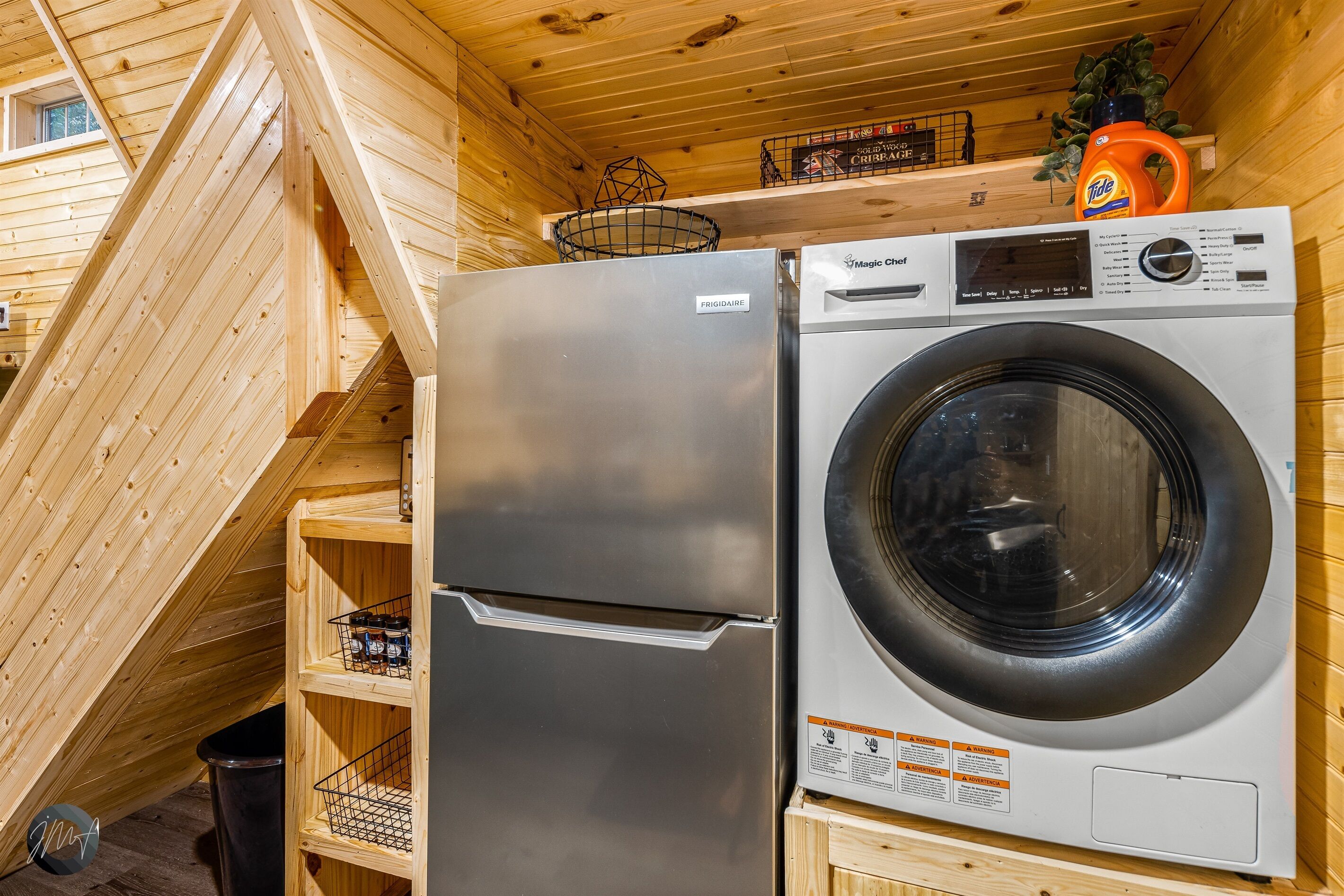 A compact kitchen with a stainless steel refrigerator and a front-loading washing machine.
