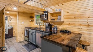 Eine kleine Küche mit Holzwänden, einer eingebauten Mikrowelle und einer Kaffeemaschine.