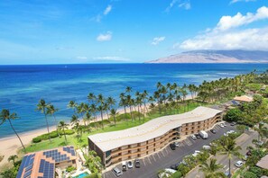 Un hôtel doté d’un toit incurvé, d’un parking et offrant une vue sur l’océan et la plage.
