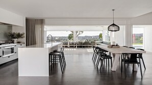 A modern kitchen with a central island, a dining area with chairs, and a view of the countryside. - Amileka - luxury 25 acre estate with pool (Federal)