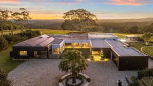 A modern house with a large patio, a swimming pool, and a view of the surrounding landscape. - Amileka - luxury 25 acre estate with pool (Federal)
