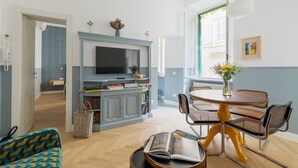 A modern living room with a TV, bookshelves, a dining table, and a sofa.