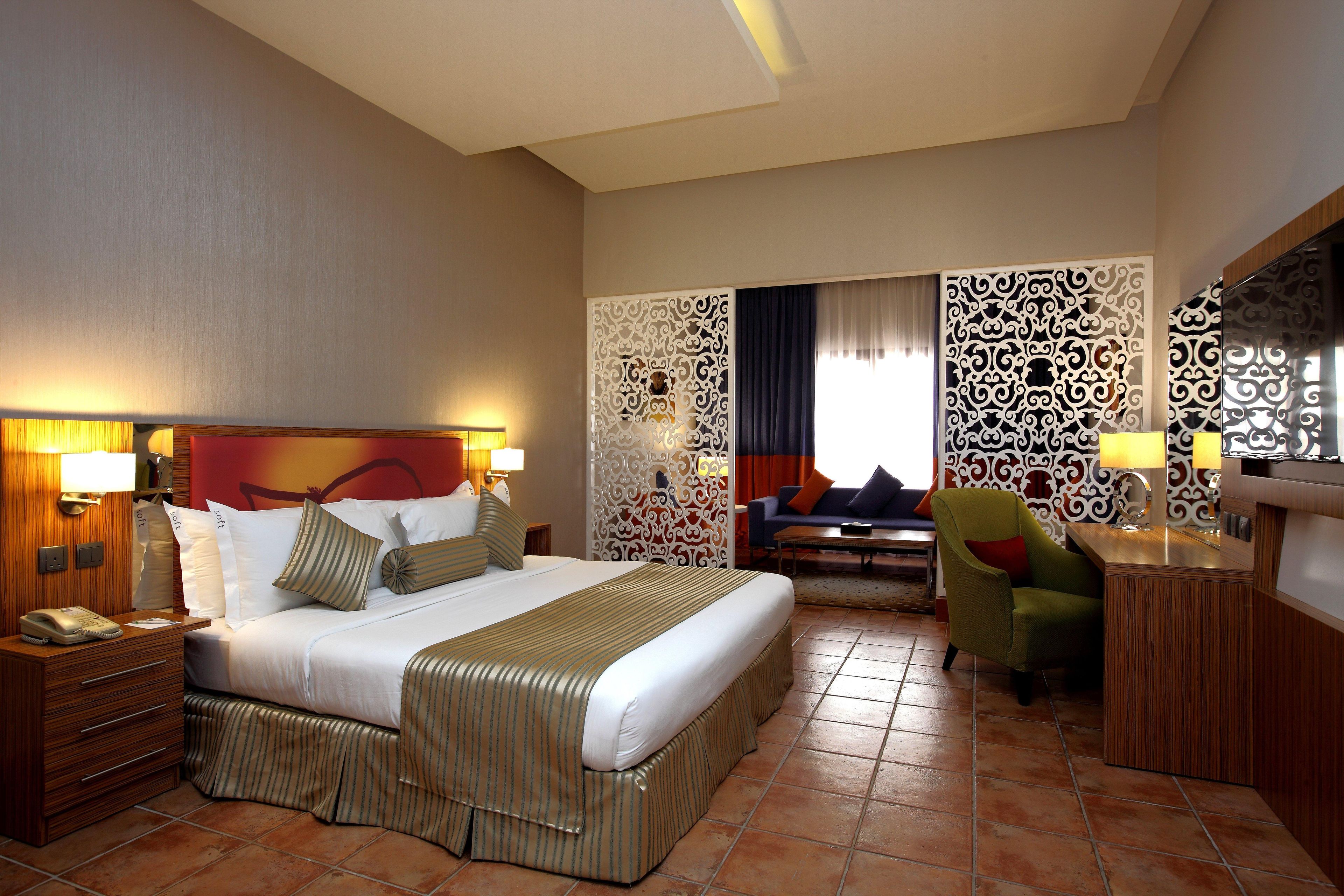 A hotel room with a large bed, a desk, a chair, and a sofa.