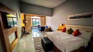 A hotel room with a bed, a desk, a chair, a TV, and a view of the outdoors. - Mena Holiday Beach Resort Half Moon Bay (Dammam)