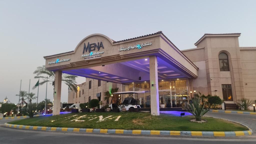 A Holiday Beach Resort with a covered entrance, palm trees, and a well-maintained lawn.