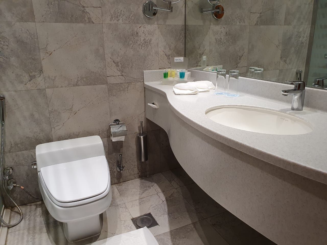 A bathroom with a toilet, sink, and mirror.