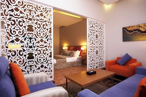 Une chambre d’hôtel comprenant un lit, un canapé, une table basse et des panneaux décoratifs blancs.