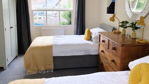 A bedroom with a bed, a dresser, a mirror, and a window with curtains.