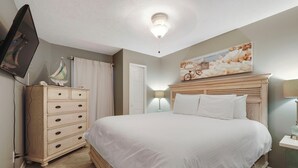 A bedroom with a bed, dresser, and a painting on the wall. - 103 Pointes North Inn | Downtown Charlevoix | Indoor/Outdoor Pool (Charlevoix)