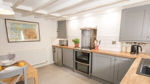Una cocina moderna con armarios grises, encimera de madera, horno integrado y hervidor.
