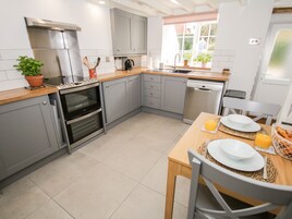 A modern kitchen with grey cabinets, a built-in oven, a dishwasher, and a dining area with a table set for two.
