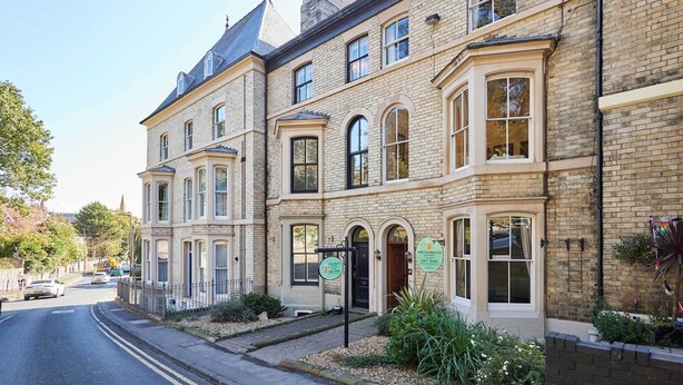 A row of traditional brick buildings with arched windows and a sign indicating a hotel. - Host & Stay | The Captain's Loft (Whitby)