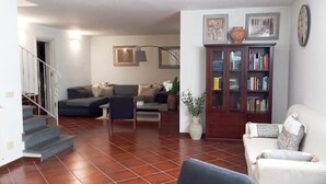 Ein Wohnzimmer mit Treppe, Sofa, Couchtisch und Bücherregal.
