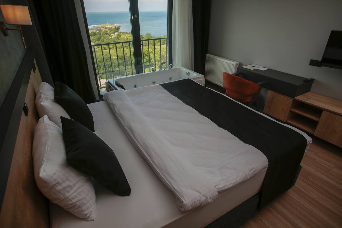 Ein Hotelzimmer mit Bett, Schreibtisch, Stuhl und Meerblick.