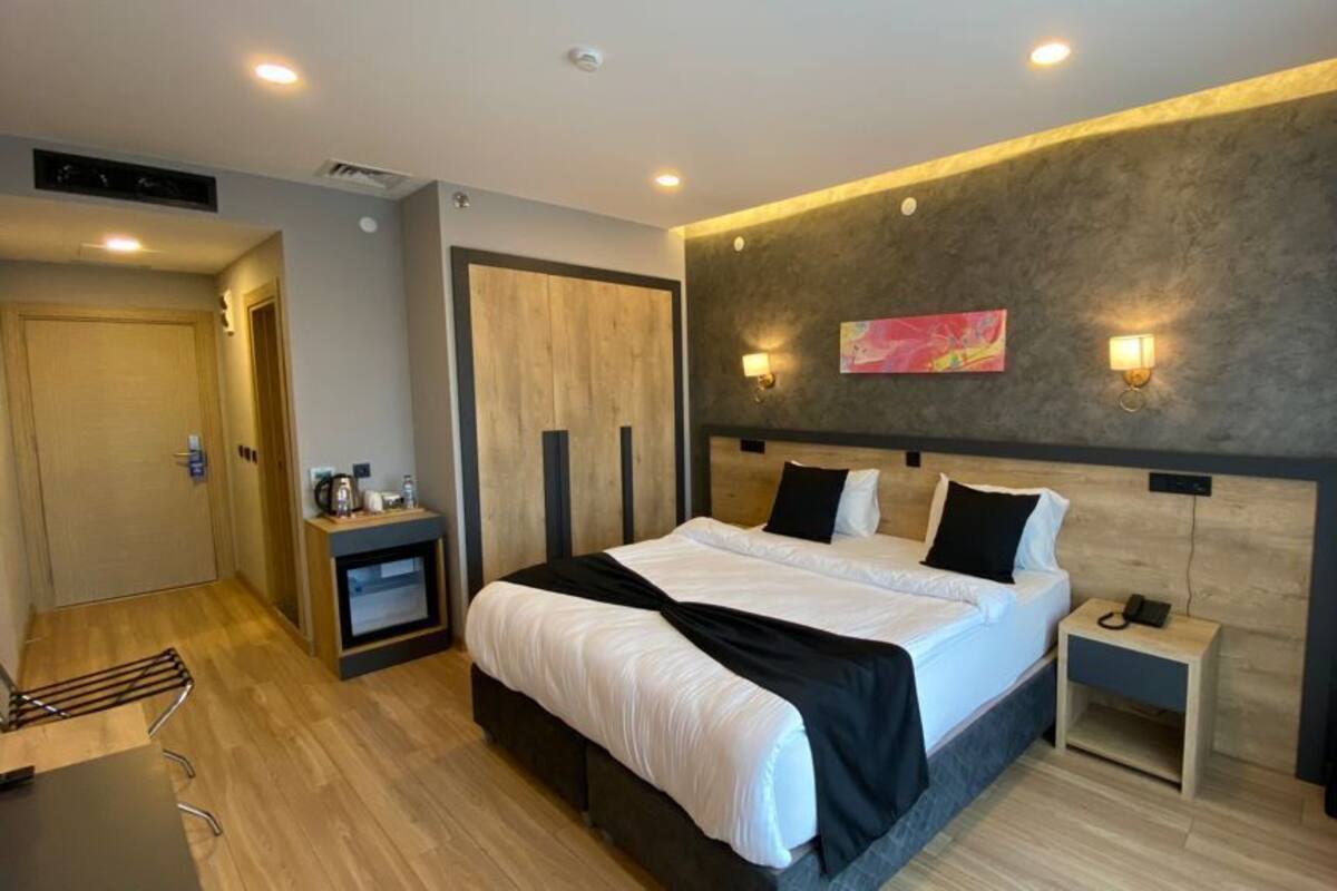 Ein modernes Hotelzimmer mit einem großen Bett, Nachttischen, einem Kleiderschrank und einer kleinen Sitzecke.