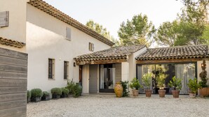 A building with a tiled roof, a gravel driveway, and potted plants. - Vacation rental house with pool LOURMARIN LS2-385 (Lourmarin)