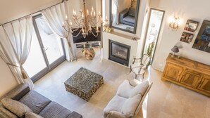 A spacious living room with a fireplace, a chandelier, and a large window with curtains. - Vacation rental house with pool LOURMARIN LS2-385 (Lourmarin)