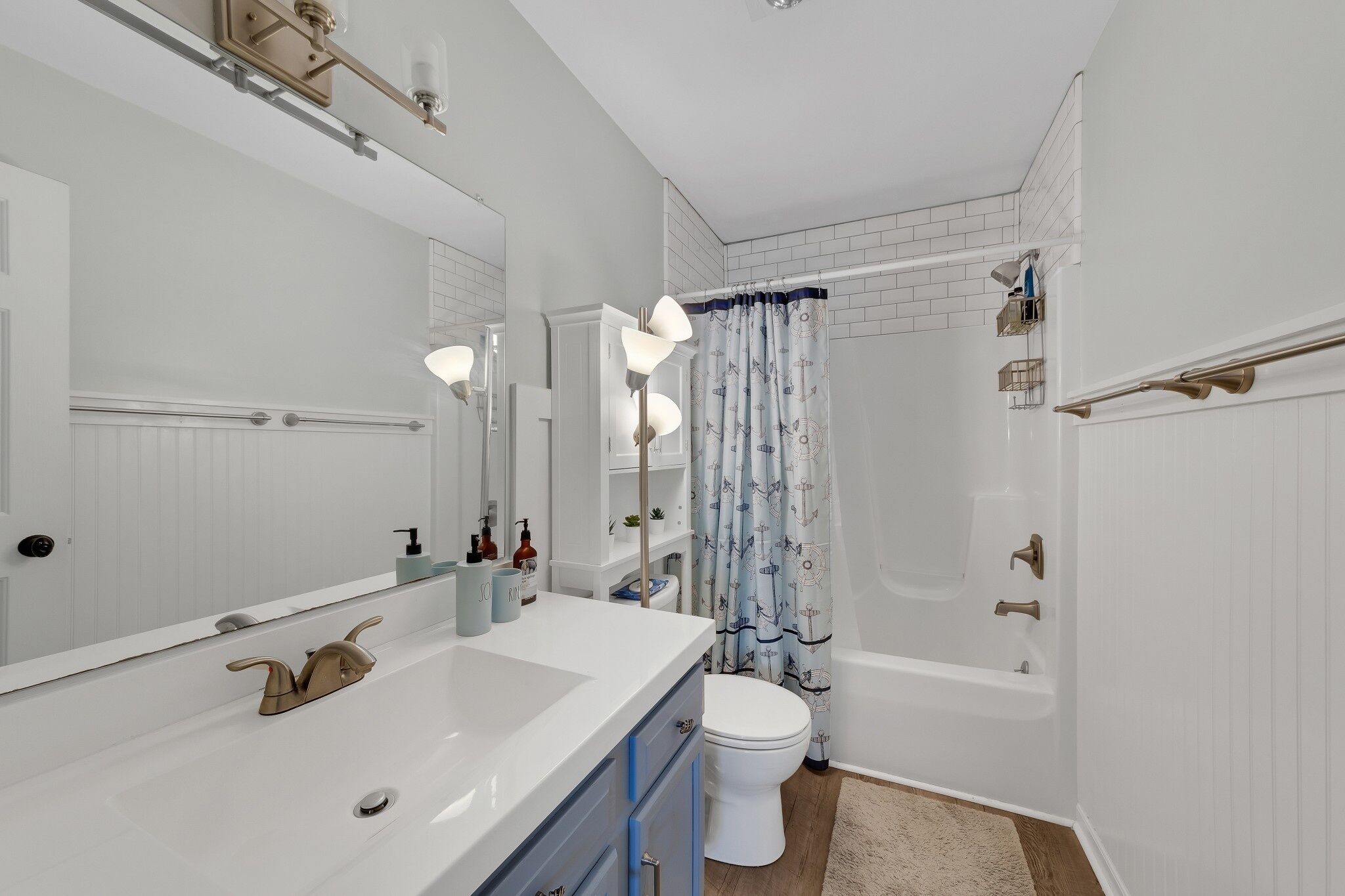 A modern bathroom with a white vanity, a large mirror, a bathtub, and a shower curtain.