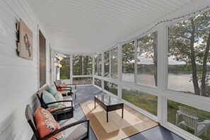 A covered porch with wicker furniture, a glass table, and a view of a lake. - Jcr Taunton Bay Hideaway 3 Bedroom Home by RedAwning (Sullivan)