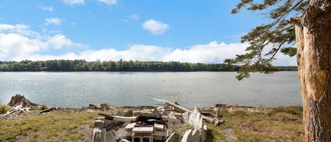 A lakeside campsite with a fire pit, surrounded by rocks and trees.