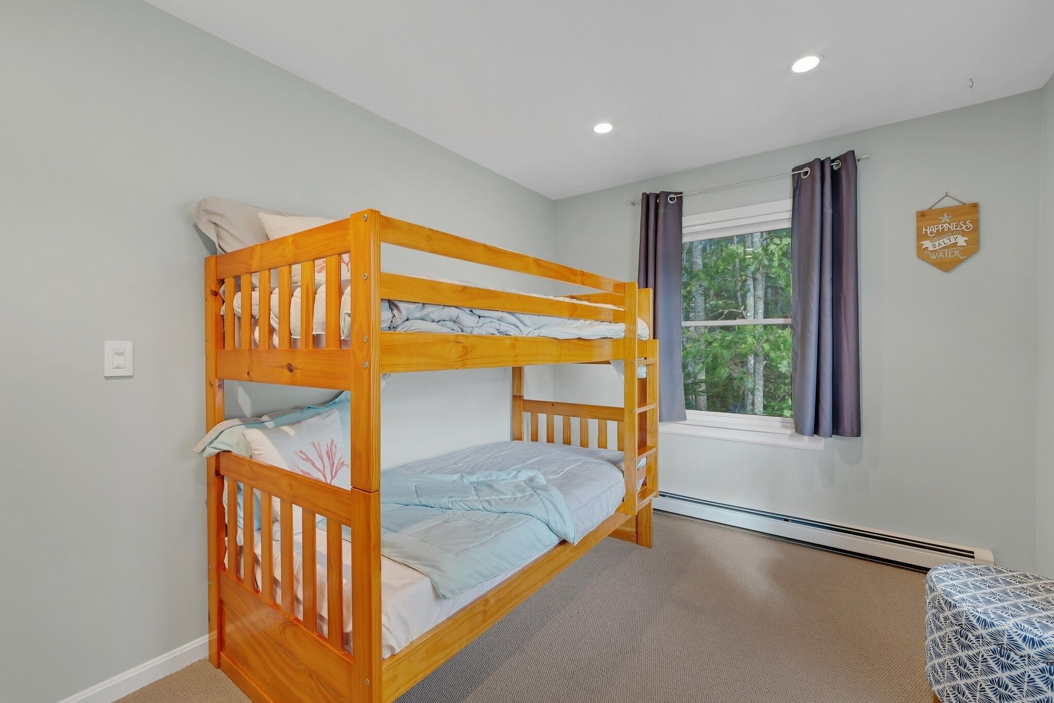 A bunk bed in a room with a window, a thermostat, and a sign on the wall.