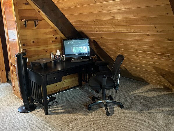 A wooden-paneled room with a desk, computer, and office chair.