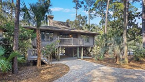 A two-story house with a balcony, surrounded by trees and a brick pathway. - River Views at Inlet Cove! Community Dock and Pool (Seabrook Island)