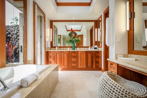 A modern bathroom with a large bathtub, wooden cabinets, and a central island with a mirror and sink. - Exquisite 4BR Hainoa Estate 122 at Hualalai – Ocean Views & Infinity-Edge Pool (Kailua Kona)