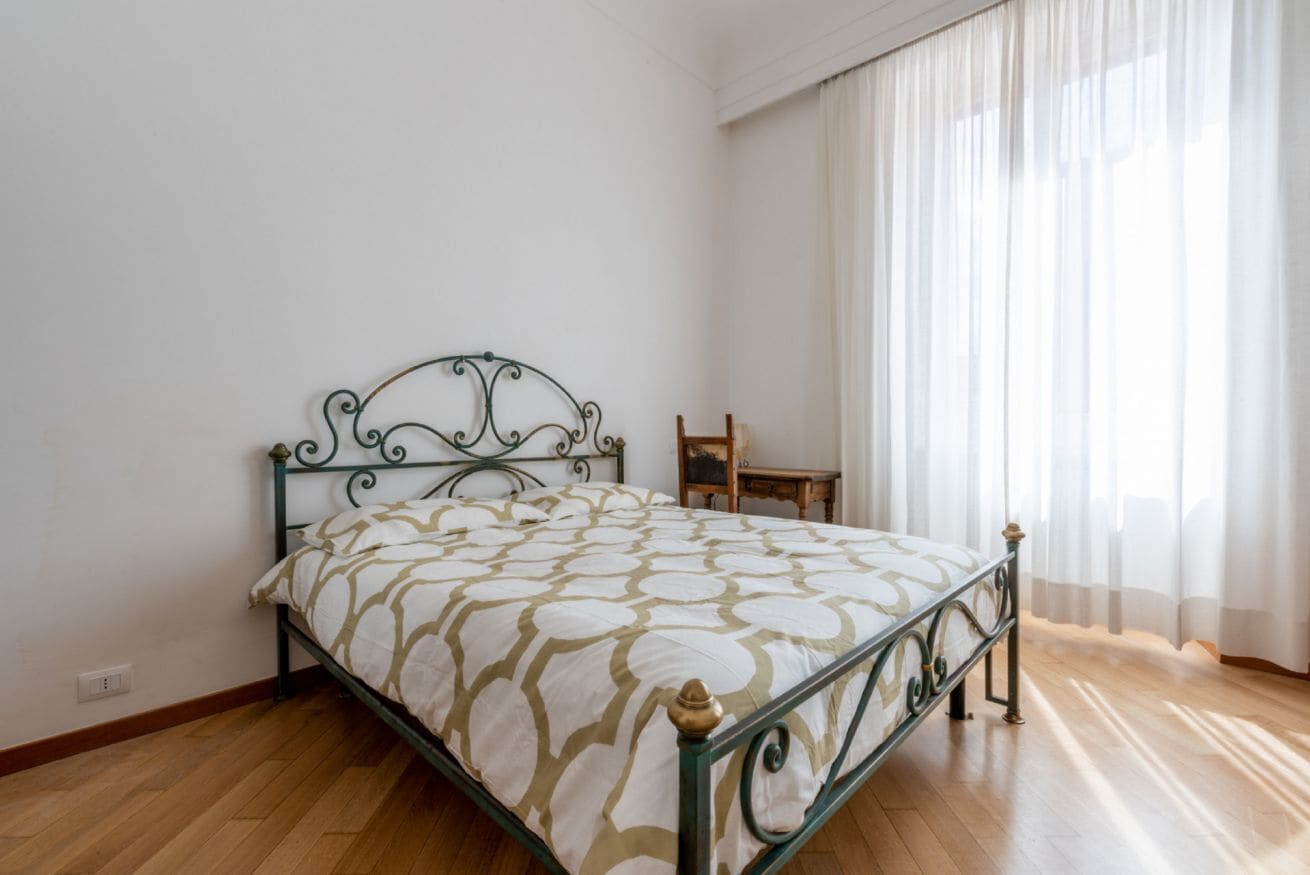 Una stanza con un letto, una sedia e una finestra con tende.