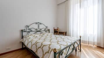 Una stanza con un letto, una sedia e una finestra con tende.