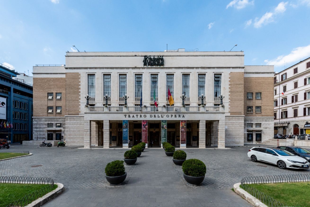Un grande edificio con un cartello che riporta 'Teatro dell'Opera' e diverse finestre.