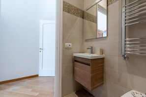 A bathroom with a wooden vanity, a mirror, and a towel rack.