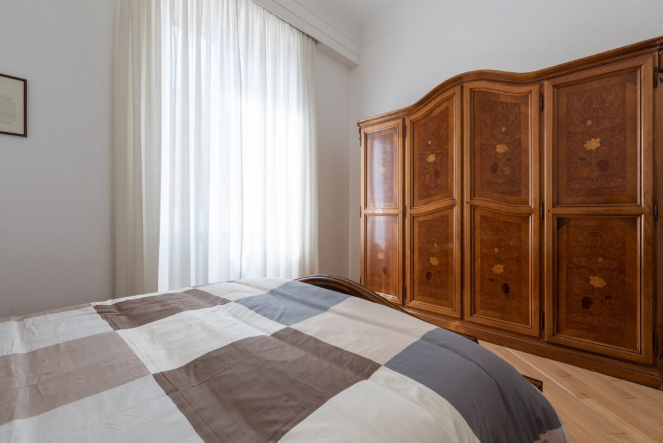 Una camera da letto con un letto, un armadio in legno e una finestra con tende.