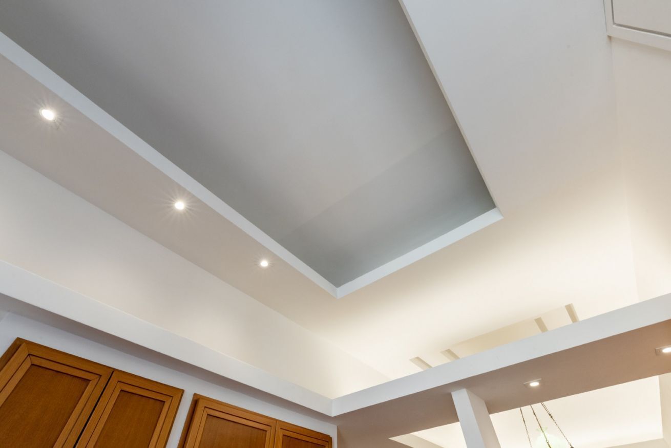 A room with a sloped ceiling, recessed lighting, and wooden cabinets.